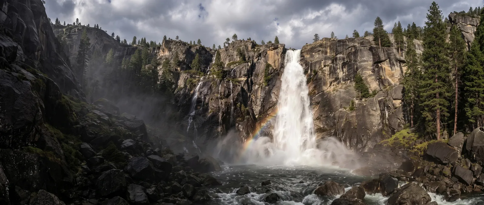 A tall waterfall plunging down a granite cliff face