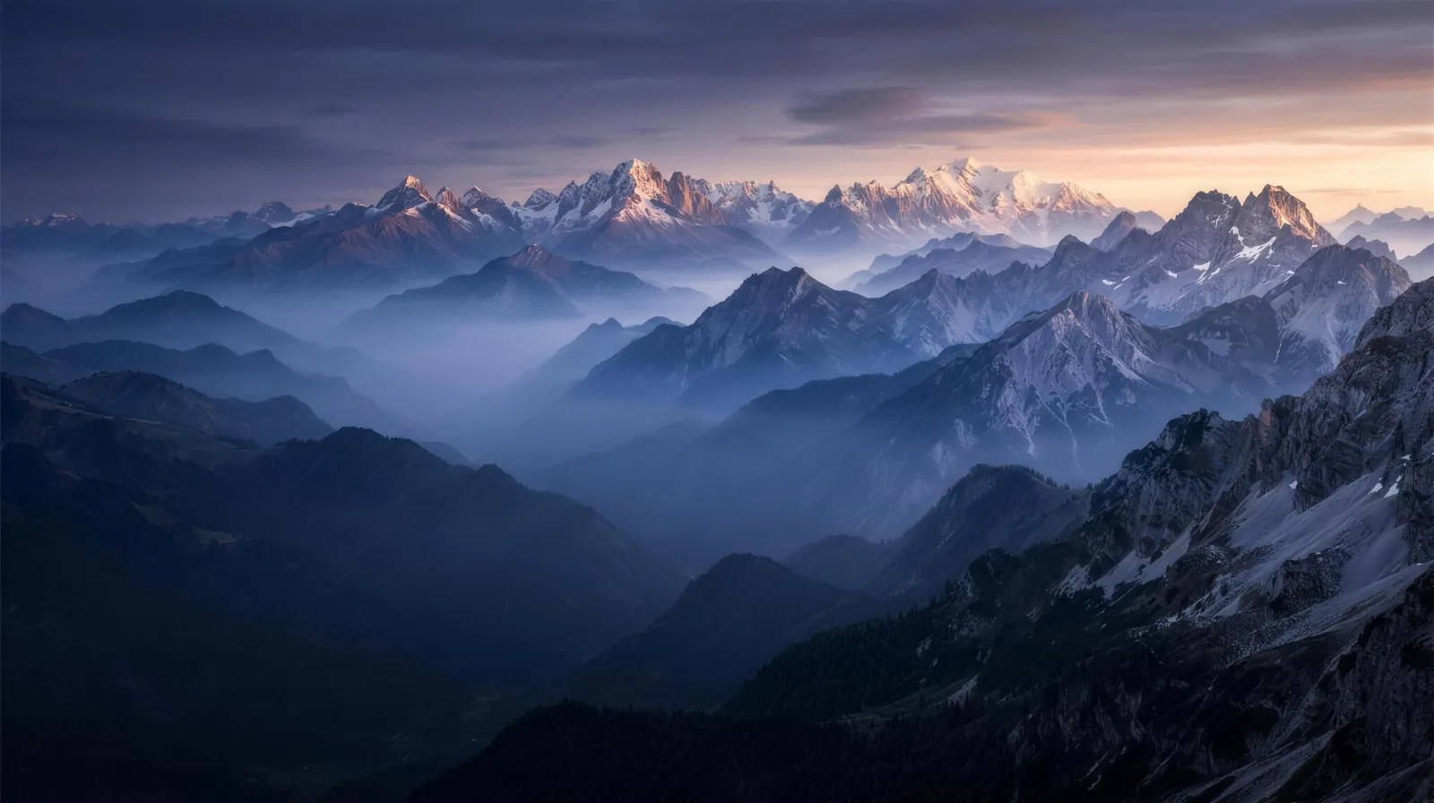 A mountain range of summits at different heights rising above a sea of clouds